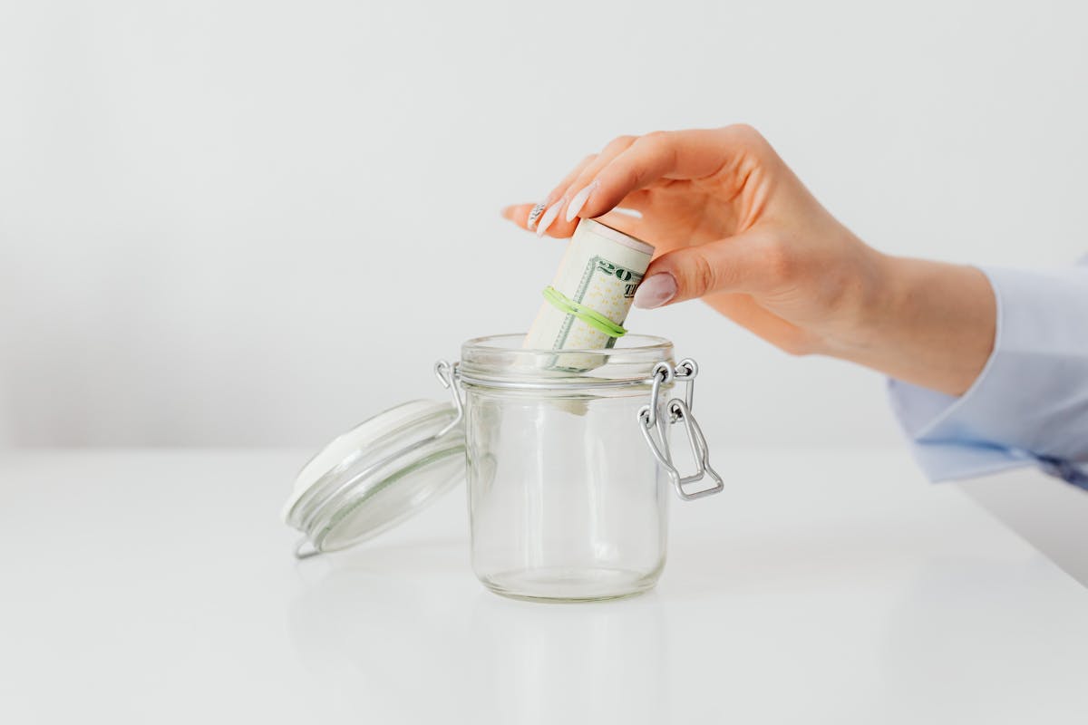 Person adding cash to a jar for sinking fund categories and annual expenses