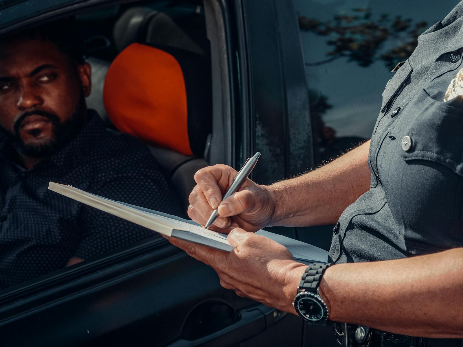 Police officer writing a traffic ticket tied to high-risk car insurance pricing